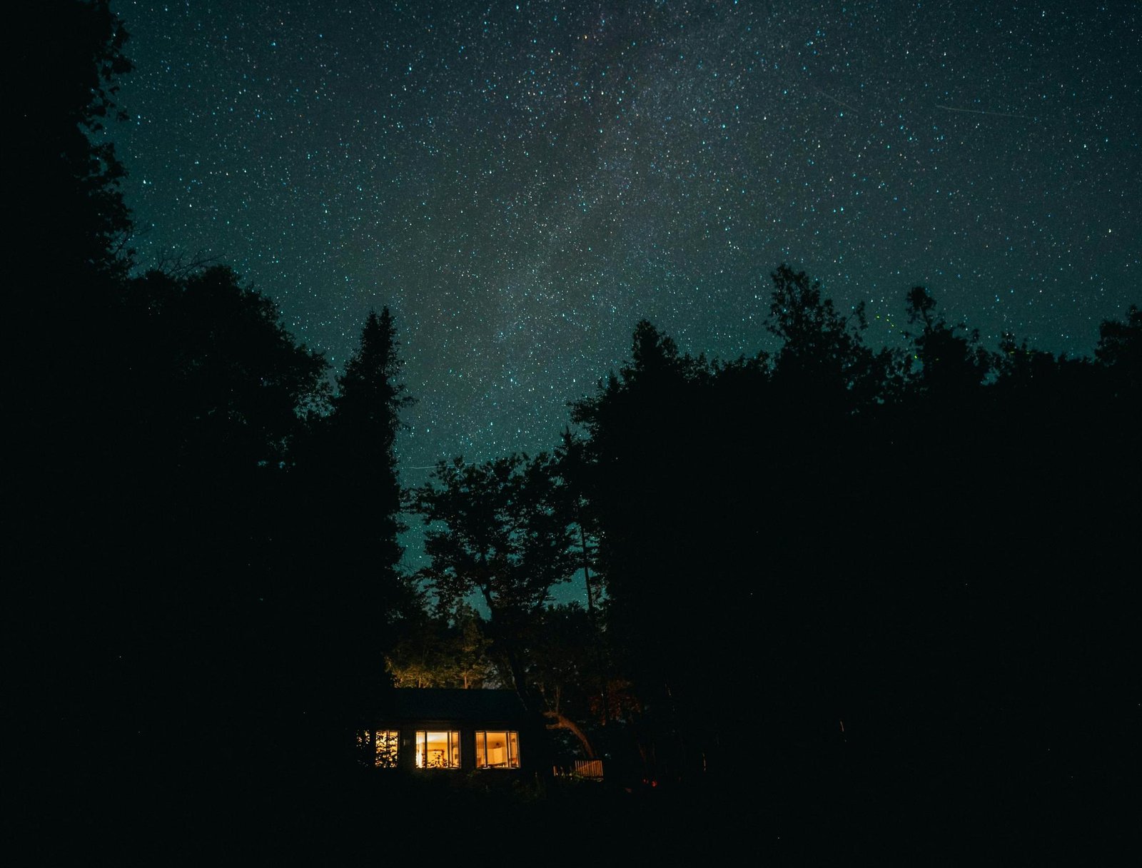 Cabană luminată noaptea, sub cerul înstelat